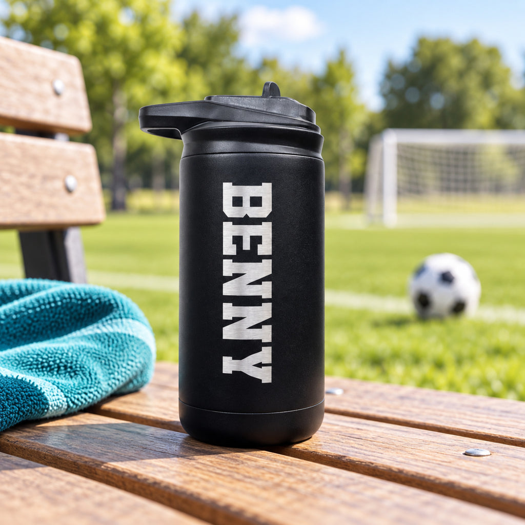 Black kids’ water bottle engraved with Benny on a bench beside an outdoor soccer field.